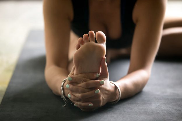 close up of a woman holding onto the sole of her feet which need a baby foot peel