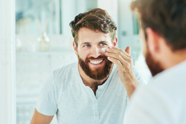 A man smiles as he looks in the mirror during No Shave November
