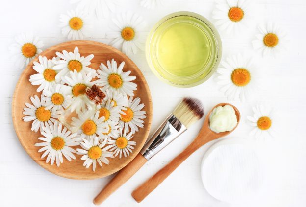 A bowl of flowers, a cup of oil, and other beauty products